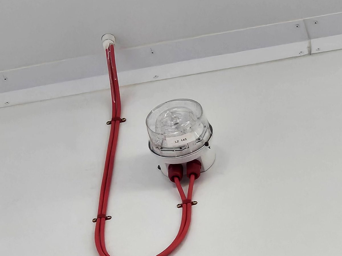 High-level fire alarm sounder beacon with red fire-rated cable, neatly clipped, in a commercial unit